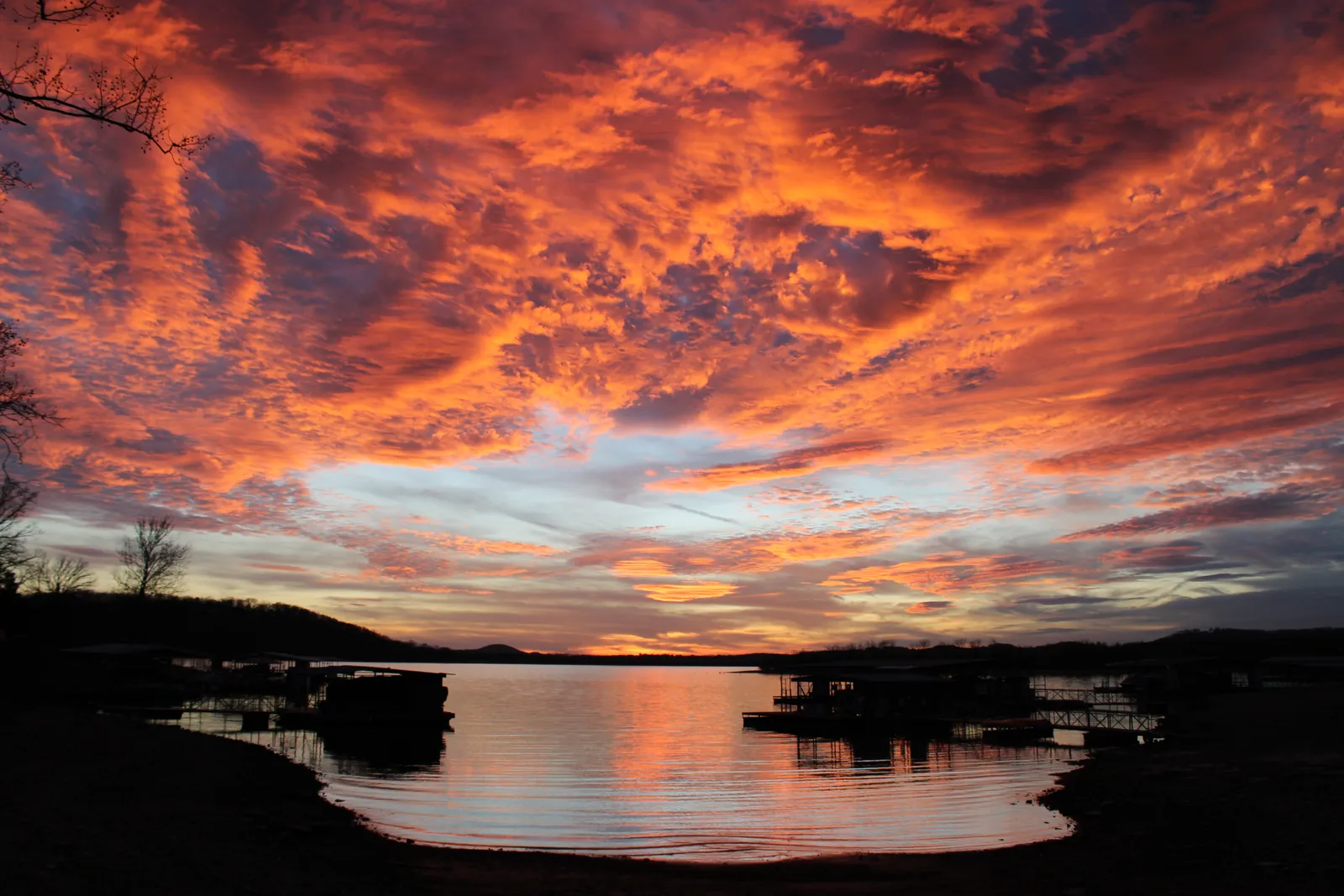 Orange sunset clouds reflected on Table Rock Lake in Missouri above silhouetted boat docks